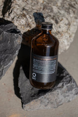 Oway Invigorating Hair & Body Wash bottle nestled between dark and pale rocks