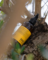 Oway Volumizing Root Spray bottle nestled among leaves and bark