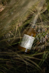 Oway RebuildM+ No-Rinse Hair Serum bottle photographed among grasses