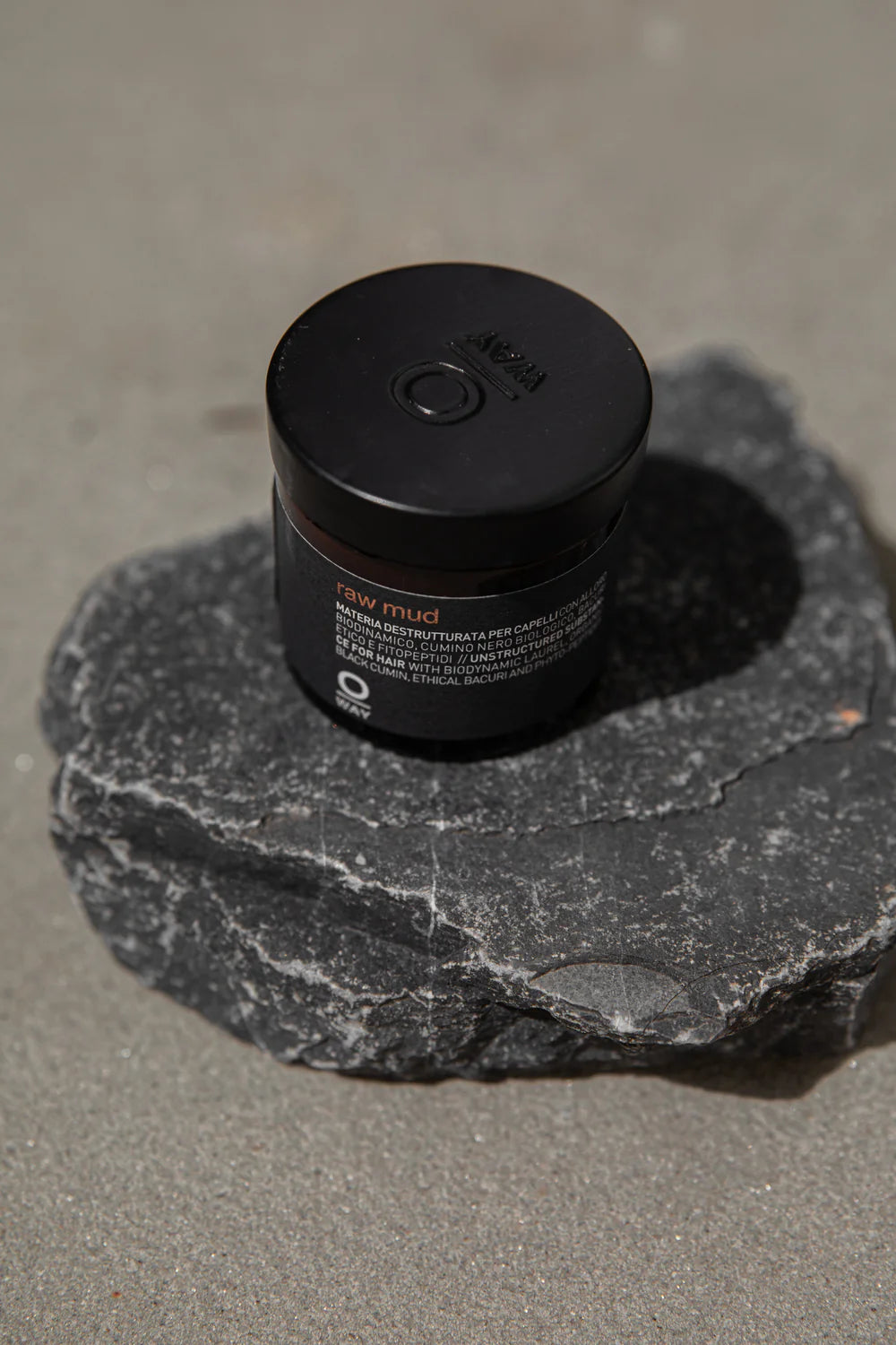 Oway Raw Mud 50ml styling paste jar photographed on dark stone