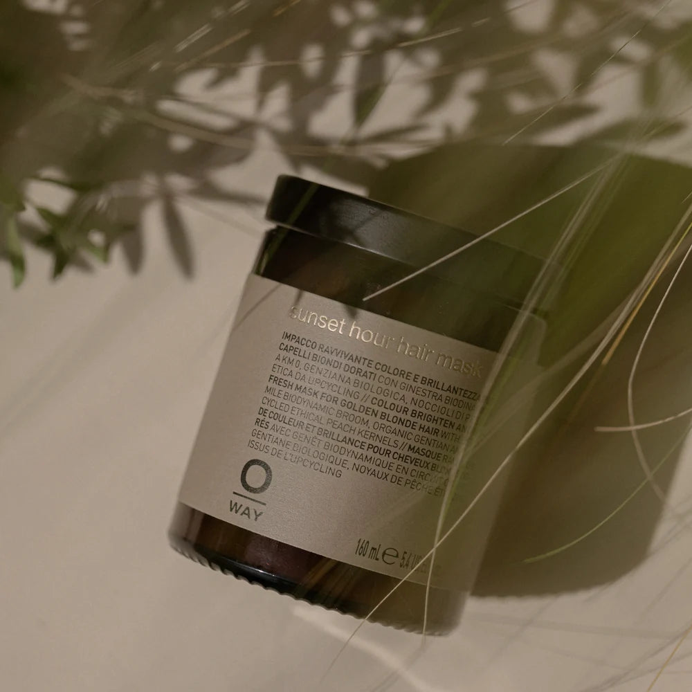 Oway Blondeway Sunset Hour Hair Mask photographed beneath green glass with soft botanical shadows