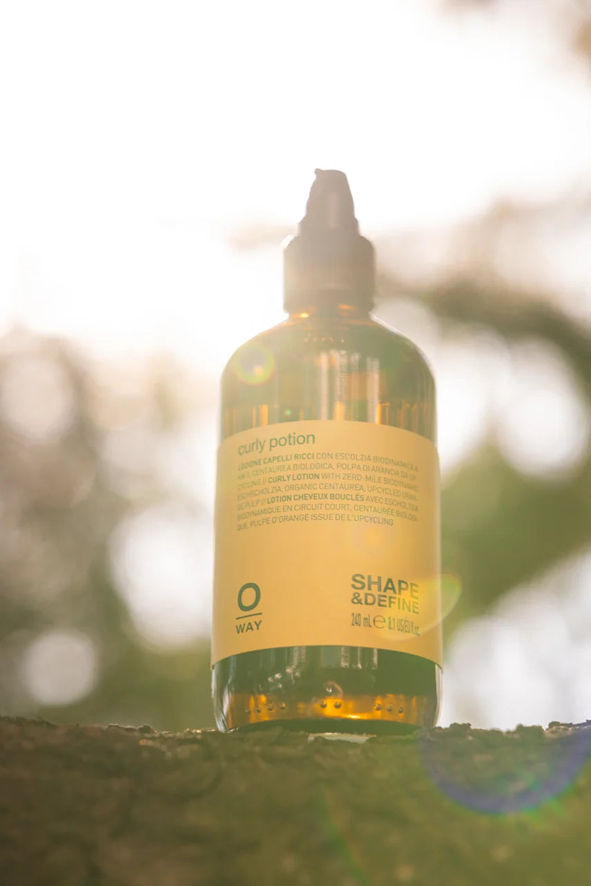 Oway Curly Potion 240ml amber glass bottle photographed outdoors in warm natural light
