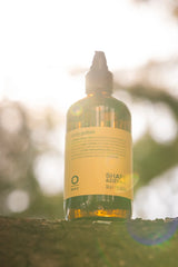 Oway Curly Potion 240ml amber glass bottle photographed outdoors in warm natural light
