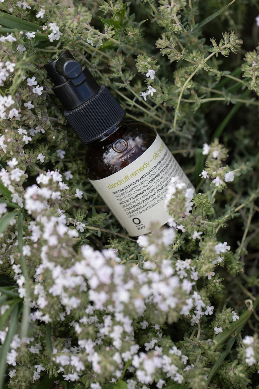 Oway Dandruff Remedy – Oily Scalp bottle photographed among flowering thyme