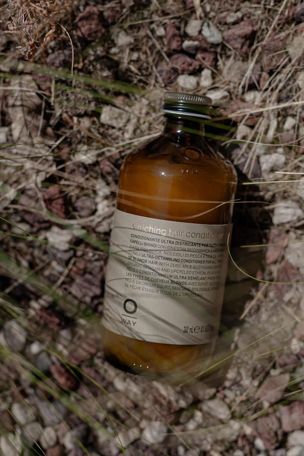 Oway Blondeway Enriching Hair Conditioner photographed on a woodland floor among leaves and grasses