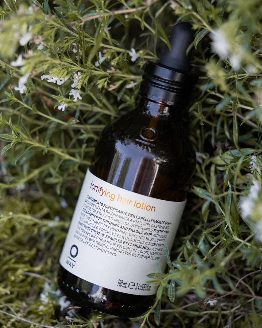 Oway Fortifying Hair Lotion photographed among herbs and white flowers
