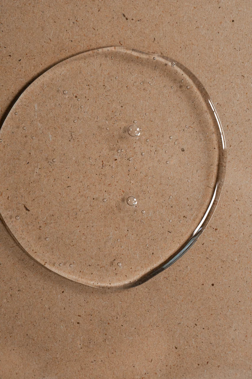 Clear Oway Invigorating Hair & Body Wash gel with small bubbles on a textured beige surface