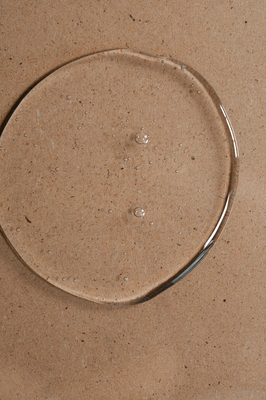 Clear Oway Invigorating Hair & Body Wash gel with small bubbles on a textured beige surface