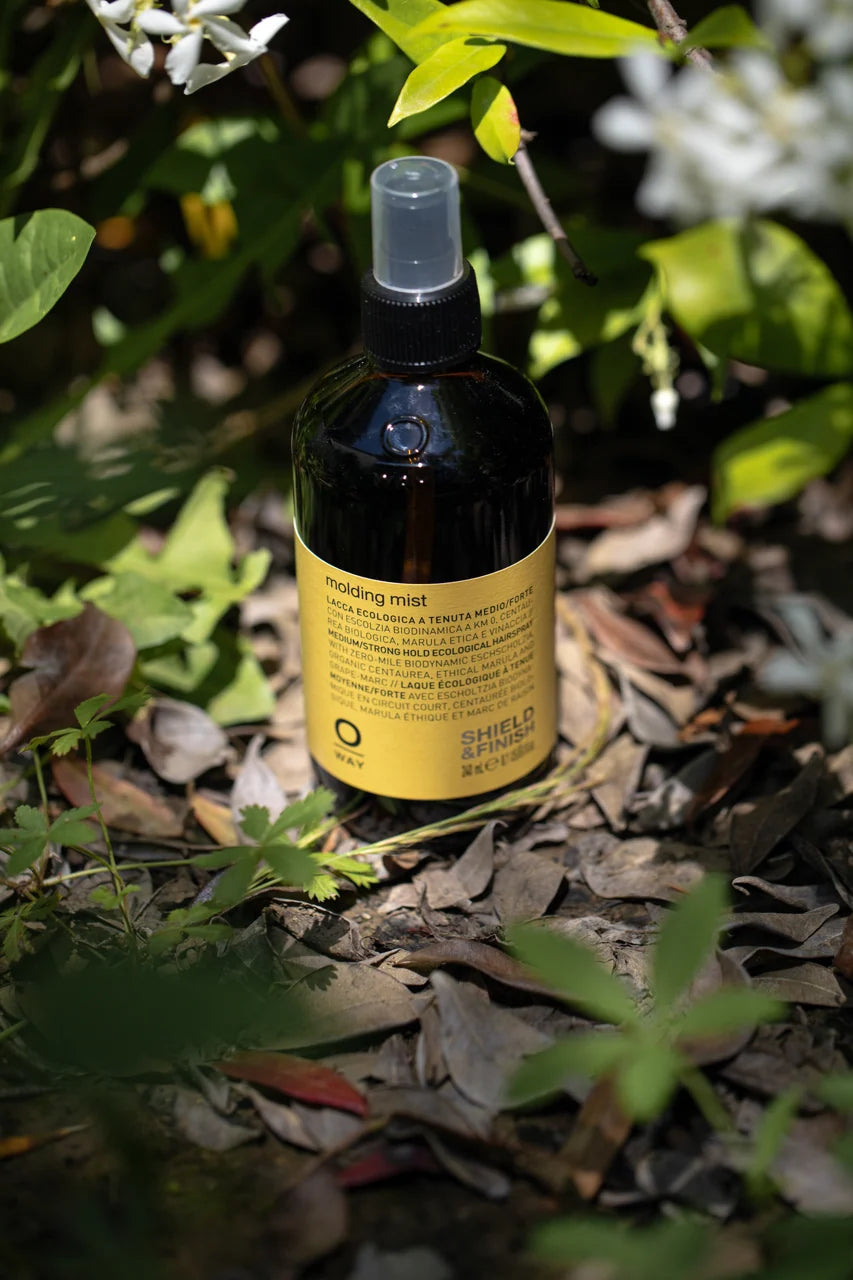 Oway Molding Mist 240ml amber glass bottle photographed outdoors among foliage