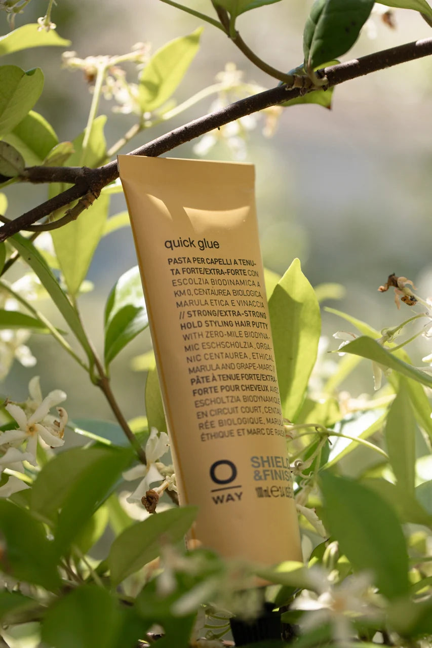 Oway Quick Glue 100ml aluminium tube among green leaves and white flowers