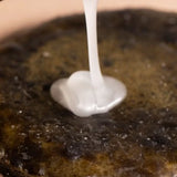Pearlescent Oway Moisturising Hair Bath shampoo pouring onto a brown surface