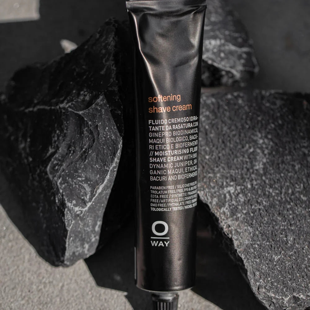 Oway Softening Shave Cream tube positioned between dark rocks