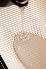 Clear Oway Volumising Hair Bath shampoo pouring onto a ridged surface