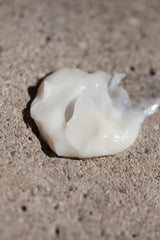 White cream texture of Oway Color Protection Hair Mask on a textured stone surface