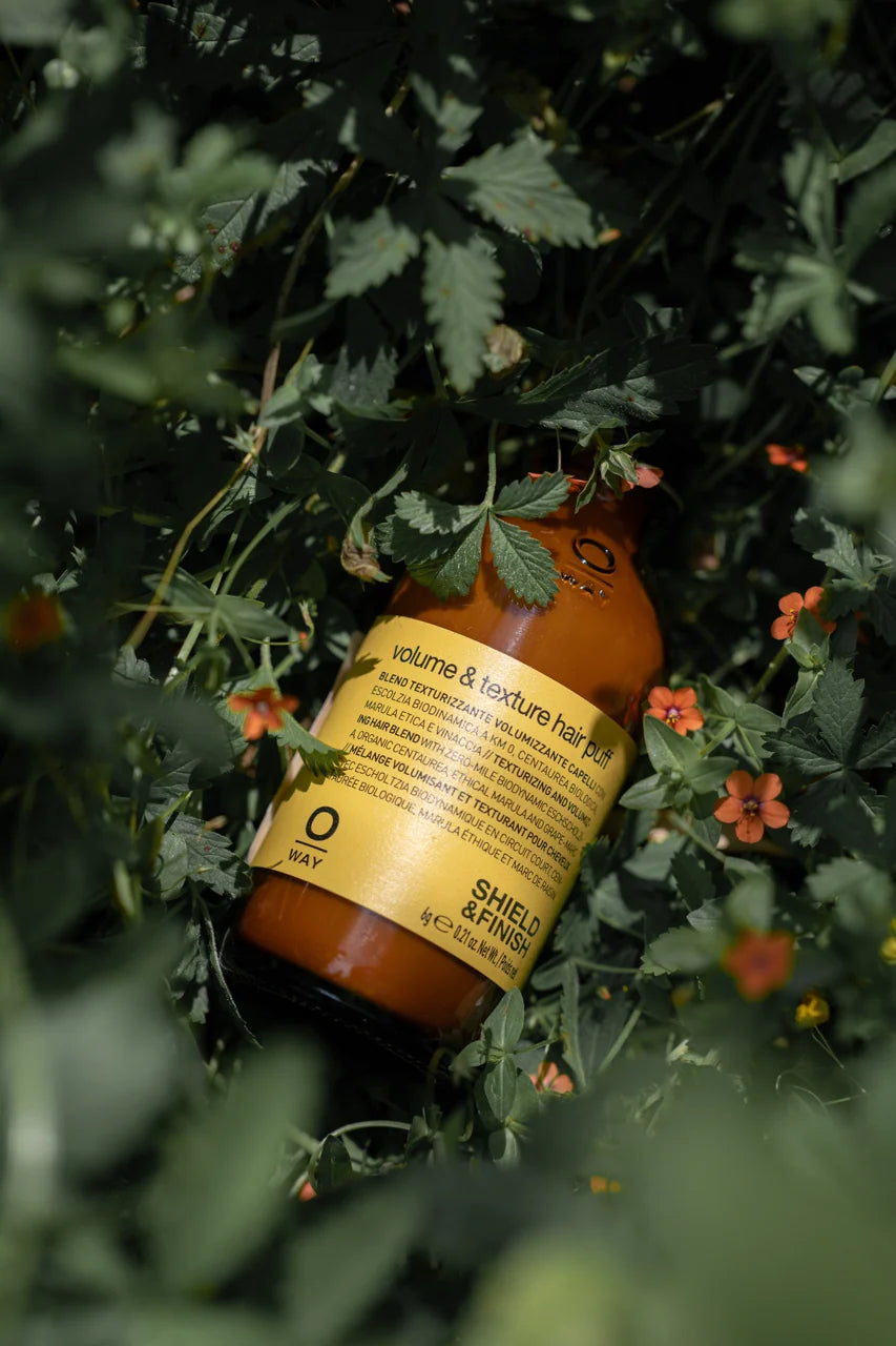 Oway Volume & Texture Hair Puff 6g bottle among green leaves and flowers