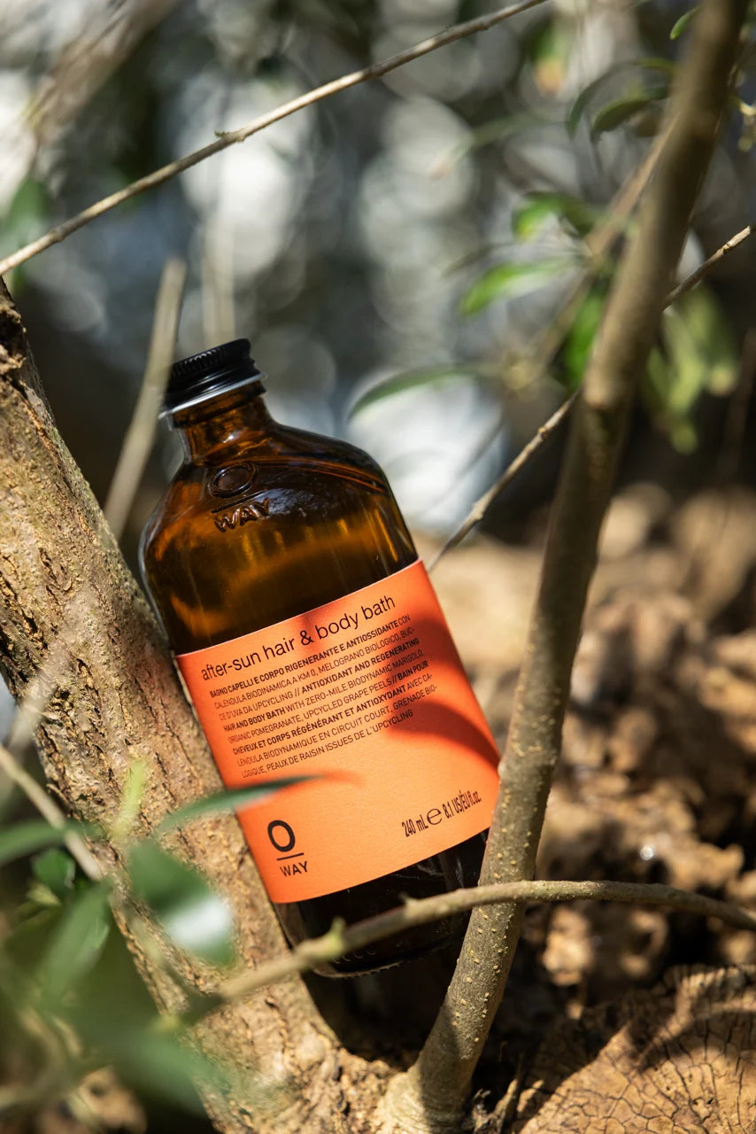 Oway After-Sun Hair & Body Bath bottle displayed outdoors among tree branches