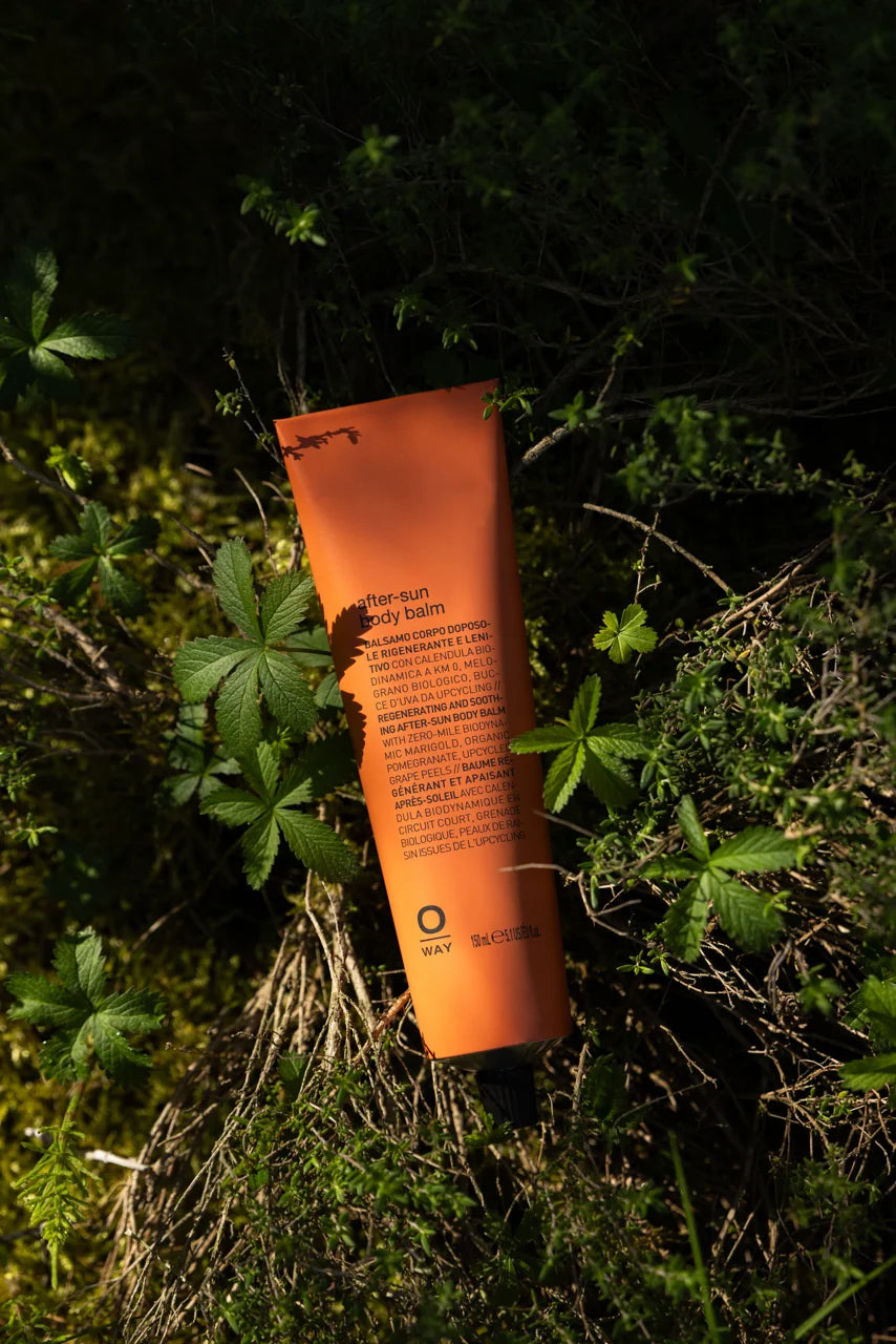 Oway After-Sun Body Balm displayed among green foliage in natural sunlight