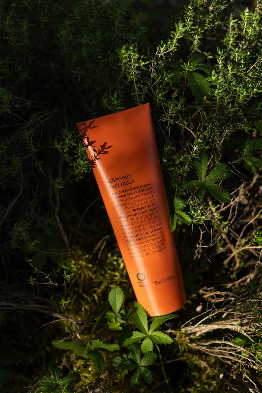 Oway After-Sun Hair Mask displayed among green foliage in natural sunlight