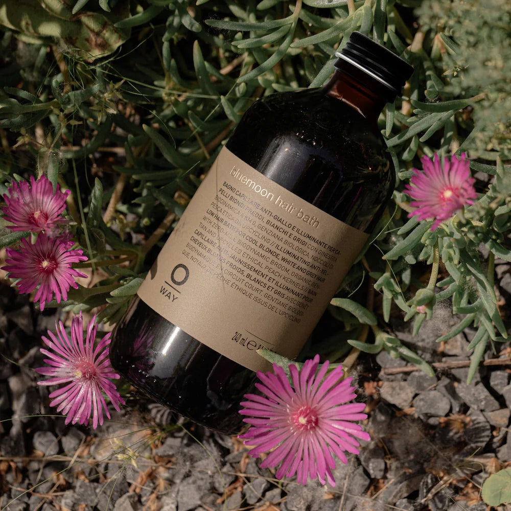 Oway Blondeway Bluemoon Hair Bath photographed among foliage and pink flowers