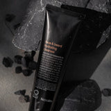 Oway Face & Beard Hydrating Cleanser tube resting among dark rocks